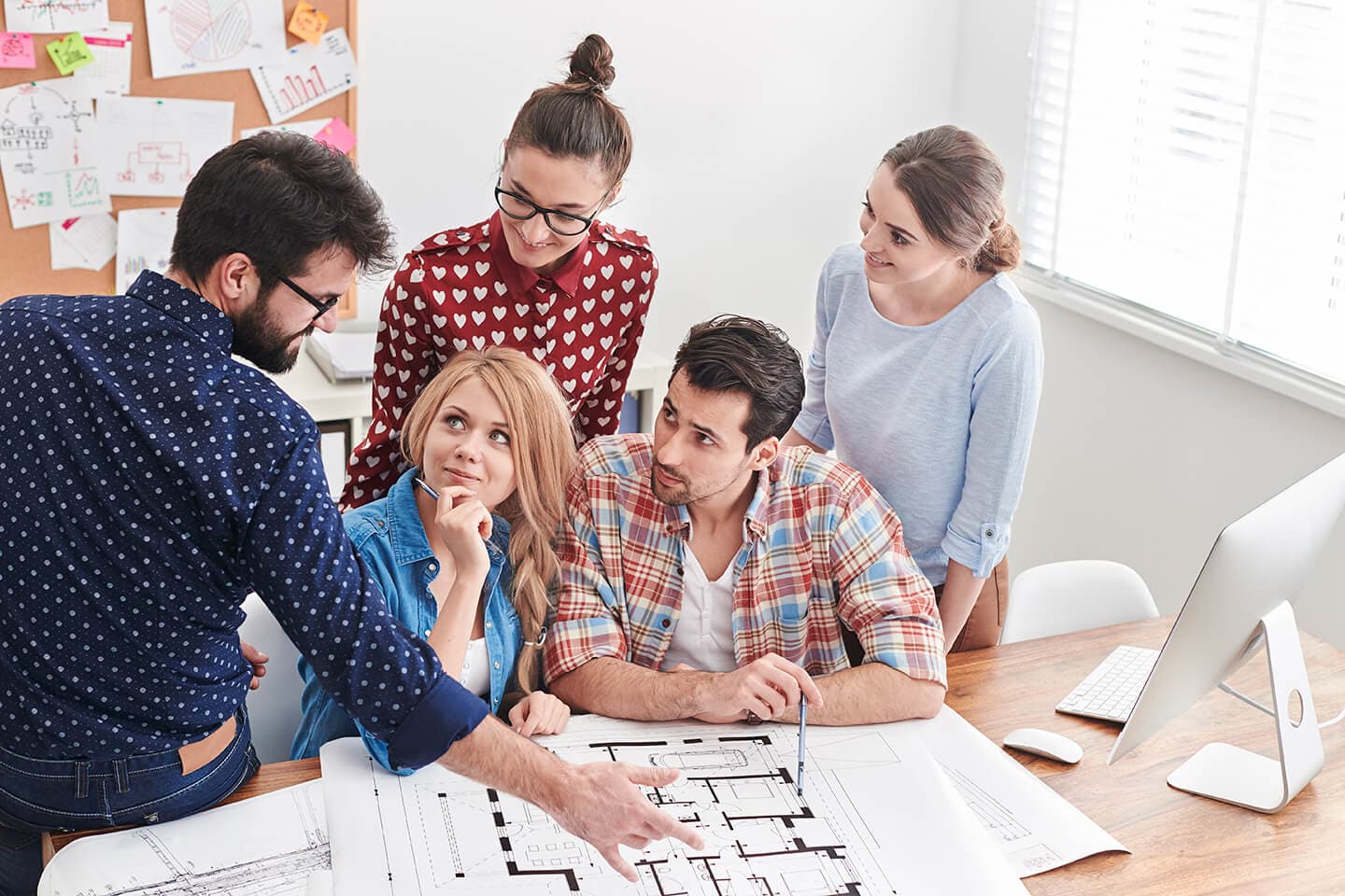 Group of architects looking at a house layout in an office