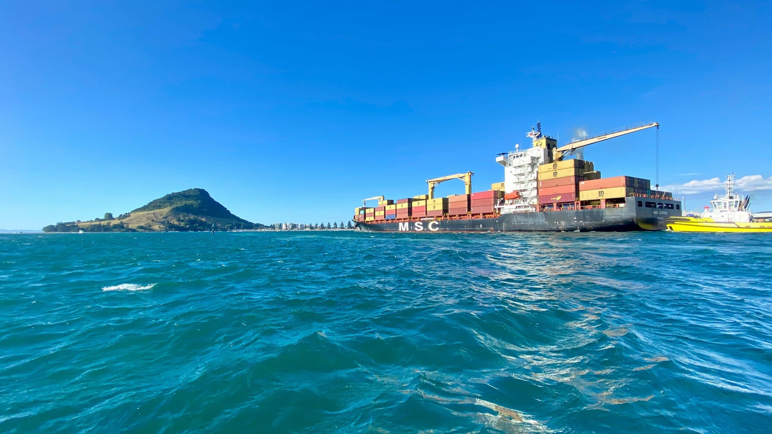 A cargo ship at the Tauranga Port with Mount Maunganui in the background